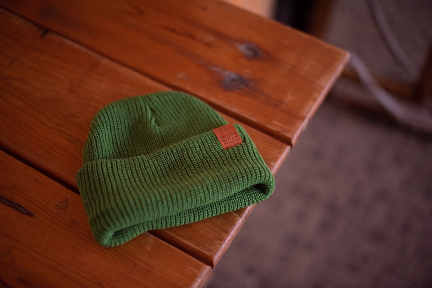 Green Falcon Ridge Ski Slopes beanie with leather patch on a wooden table